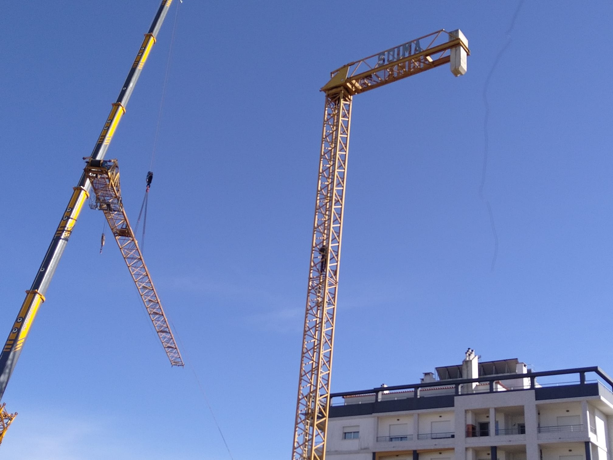 Two yellow cranes seen from below, against the sky